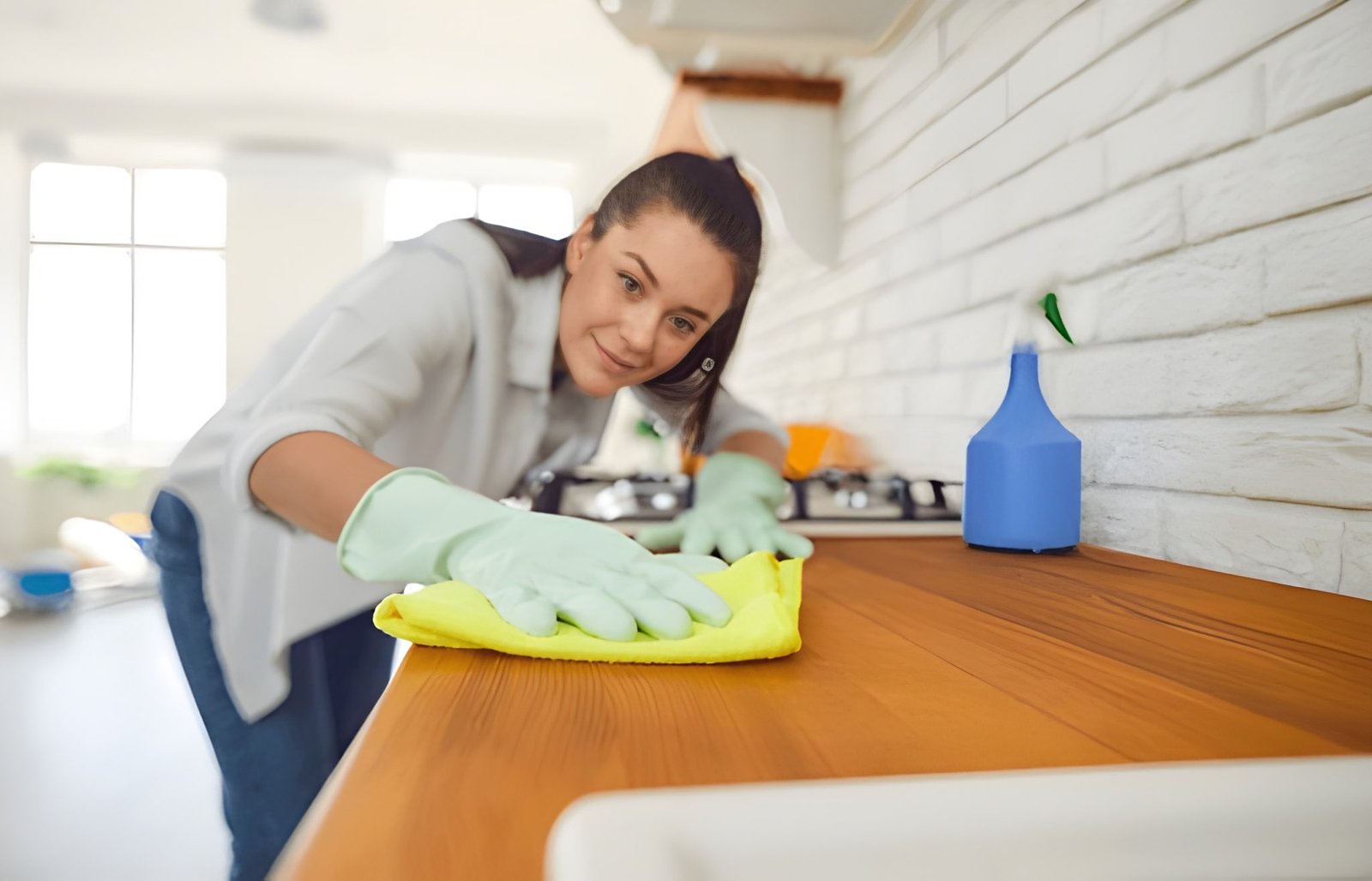 Cleaner wiping office kitchen counter with gloves and cloth, showcasing professional office cleaning in Mississauga to boost employee productivity.